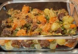 Gegratineerde aardappelovenschotel met worteltjes, doperwten, prei en braadworstballetjes
