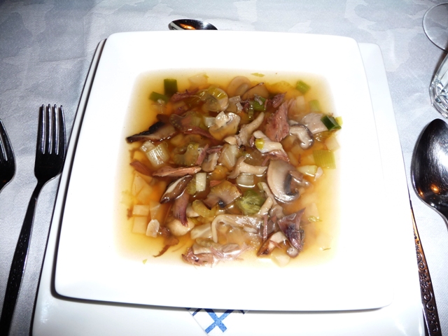 Heldere duivenbouillon met paddenstoelen garnituur