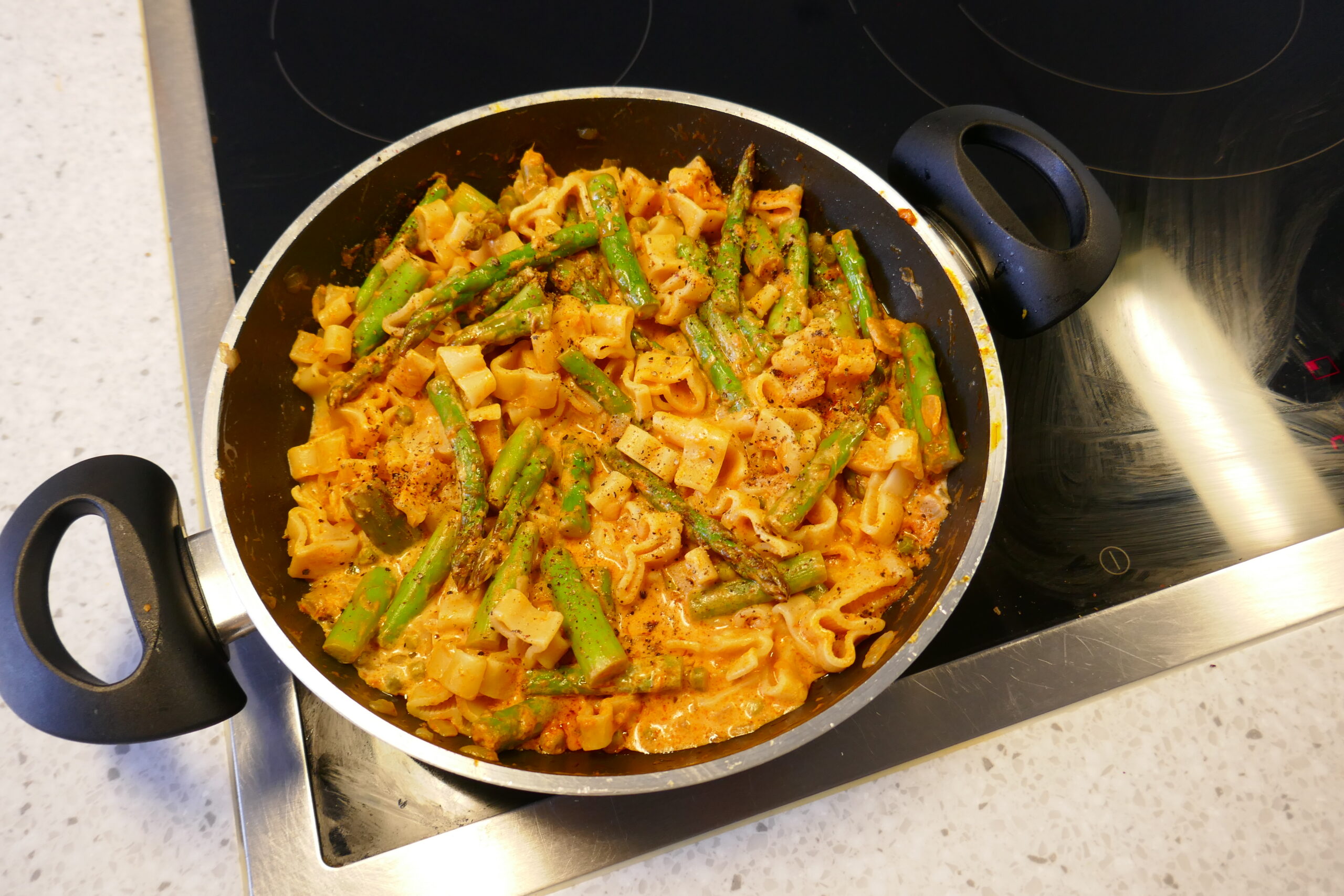 Groene asperges pasta met tuinerwtjes in een romige saus