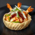 Gamba’s uit de wok in pappadam geserveerd, met prei