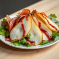Gepocheerde peer met parmaham, sla en frambozendre