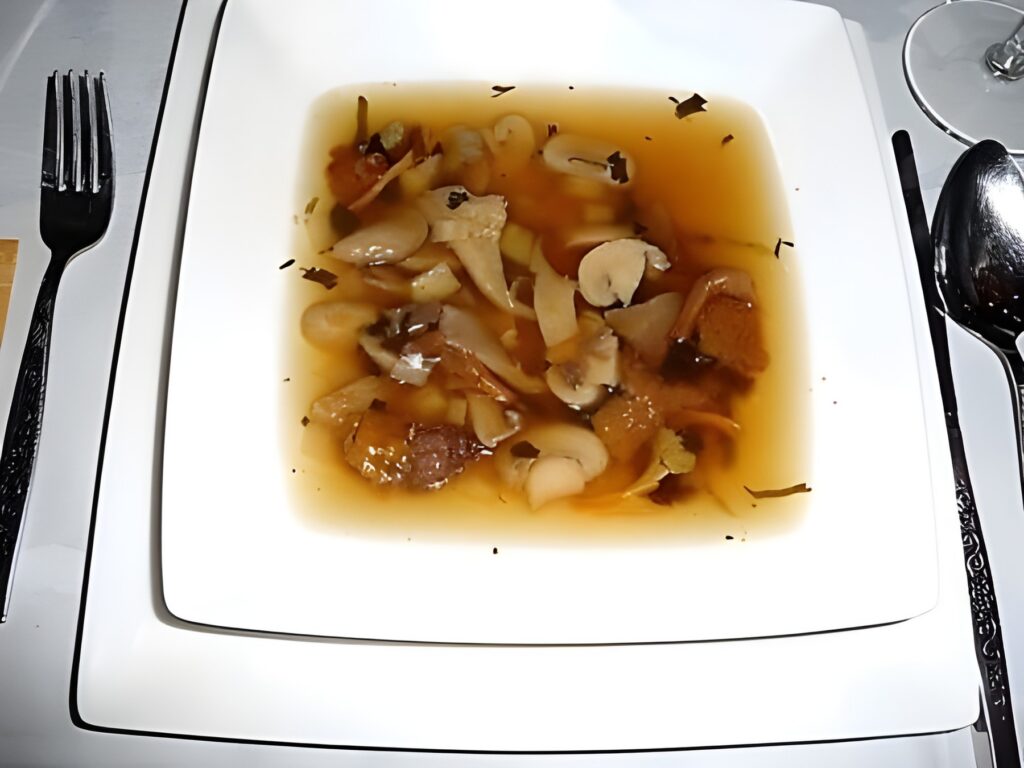 Heldere wildsoep met een garnituur van paddenstoelen