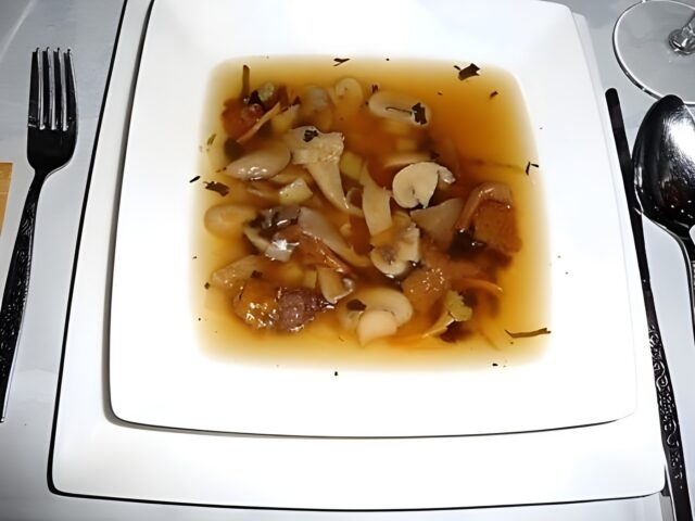Heldere wildsoep met een garnituur van paddenstoelen