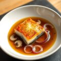 Op vel gebakken kabeljauwfilet met uienbouillon en shiitakes