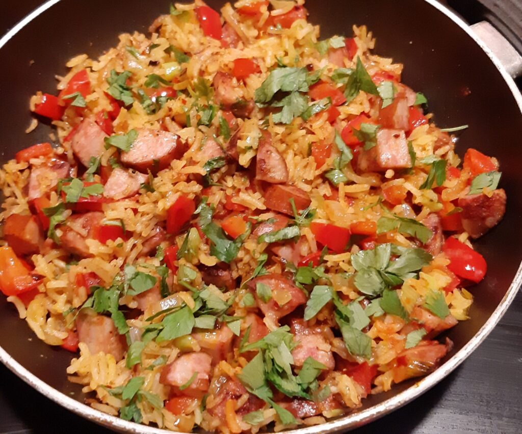 Aziatische rijst met knapperig gebakken stukjes rookworst, paprika en lente-uitjes