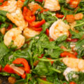 Aziatische wok met grote garnalen, spinazie en paprika