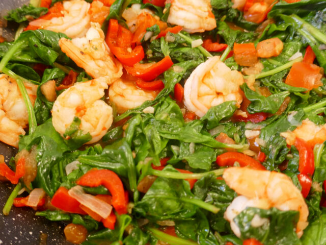 Aziatische wok met grote garnalen, spinazie en paprika