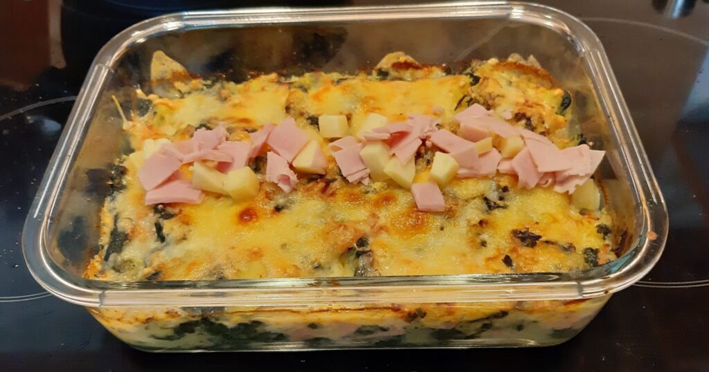 Gegratineerde ovenschotel verse spinazie met aardappel, reepjes ham en blokjes kaas