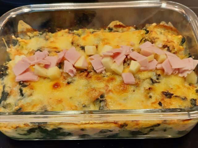 Gegratineerde ovenschotel van verse spinazie met aardappel, reepjes ham en blokjes kaas