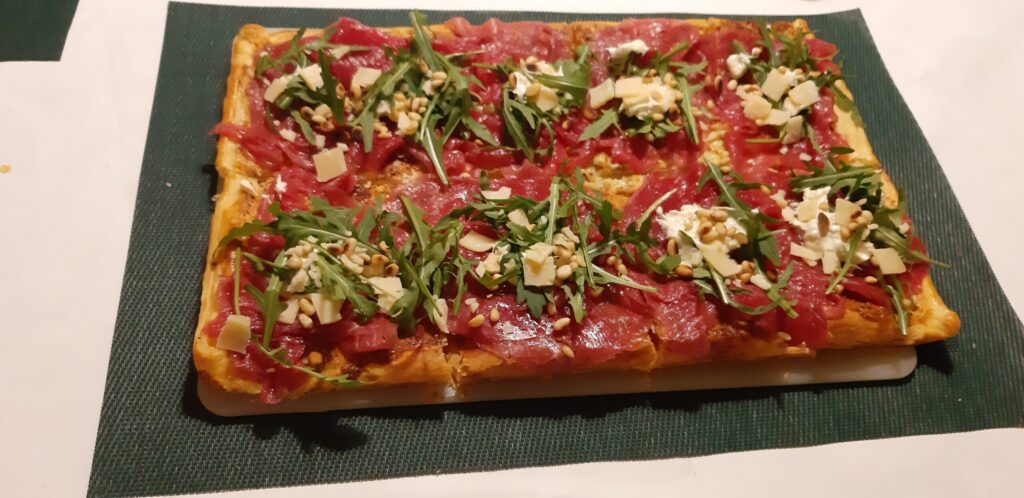 Gemakkelijke plaattaart van bladerdeeg met carpaccio, rucola en truffeltapenade