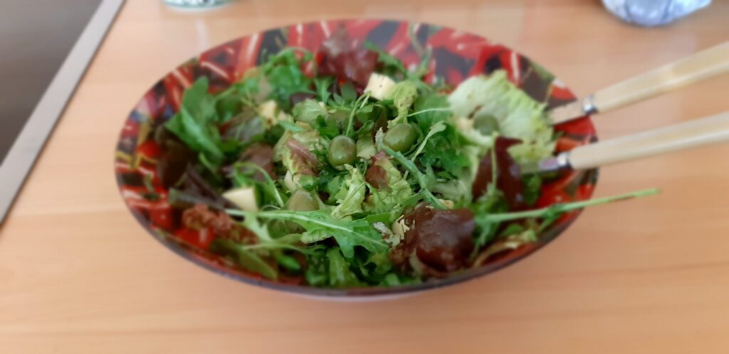 Gemengde rucola salade met witte kaasblokjes, gedroogde tomaten en olijven