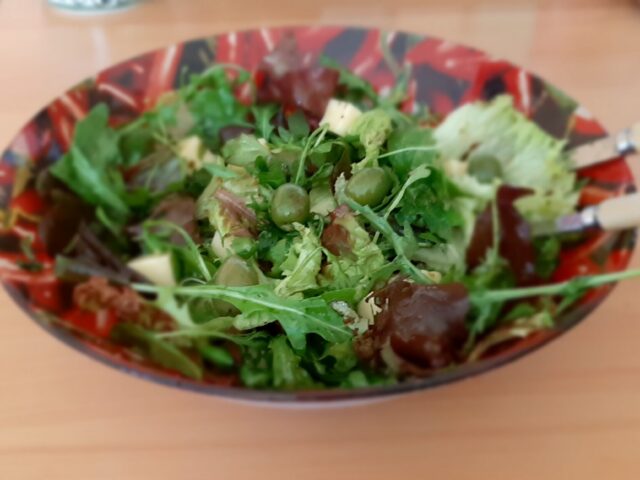 Gemengde rucola salade met witte kaasblokjes, gedroogde tomaten en olijven