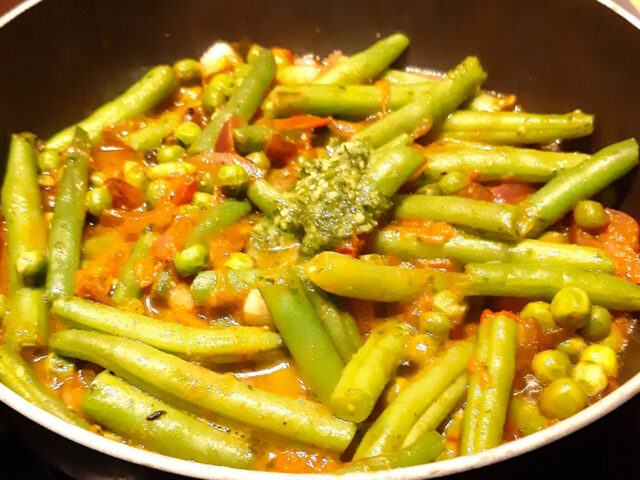 Sperziebonen gemengd met doperwten, tomaat en basilicumpesto. Een lekker Italiaans bijgerecht.