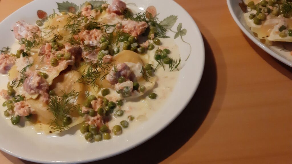 Mezzelune met een romige saus van warm gerookte zalm, doperwten en dille