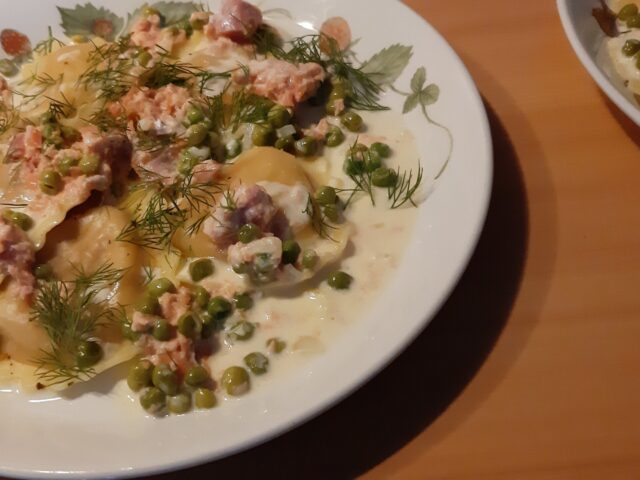 Mezzelune met een romige zalmsaus met doperwten en dille