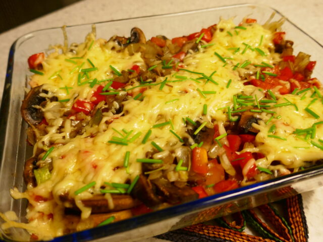 Ovenschotel met geraspte aardappel, champignons, paprika en getopt met kaas