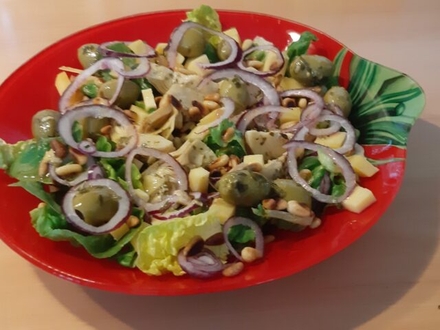 Salade met gemarineerde artisjokharten, olijven, kaasblokjes en pijnboompitten