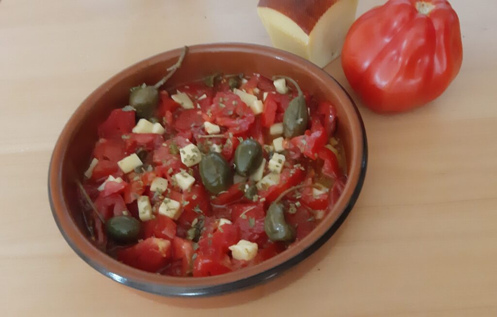 Salade van coeur de boeuf tomaten met blokjes kaas en kappertjes