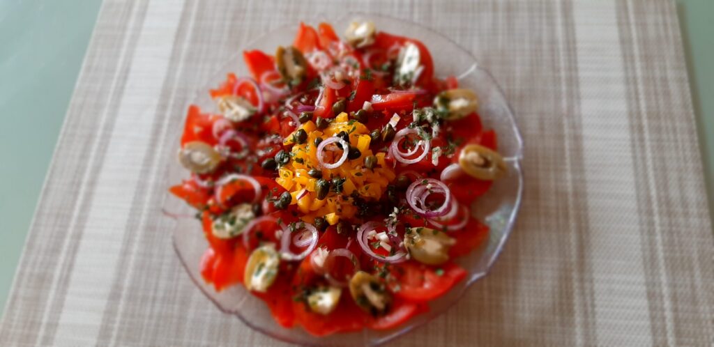 Spaanse tomaten/paprikasalade met rode ui, kappertjes en gevulde olijven
