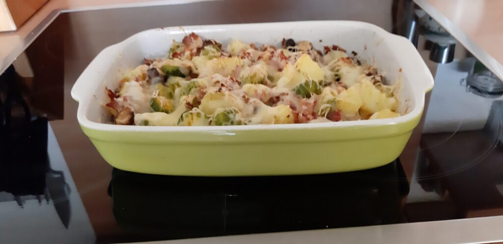 Spruitjesschotel met aardappelblokjes, pancetta, champignons en kaas