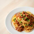 Tagliatelle bolognese met doperwtjes en gebakken ui