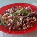 Witte bonensalade met knapperig gebakken Serranoham, gedroogde tomaatjes, Kalamata olijven en dunne reepjes rode ui.