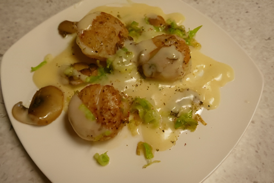 Coquilles in Champagneroomsaus met gefrituurde prei