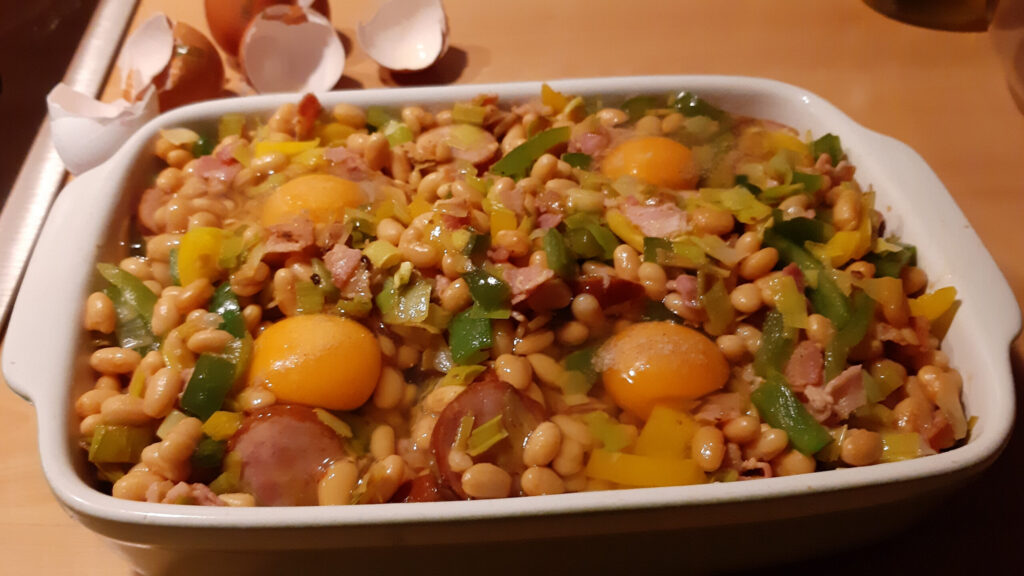 Engelse witte bonenschotel met rookworst, eieren, prei en paprika