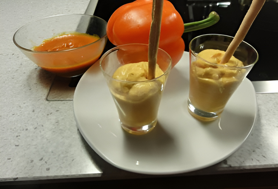 Oranje paprikamousse met roomkaas en soepstengel in een glaasje