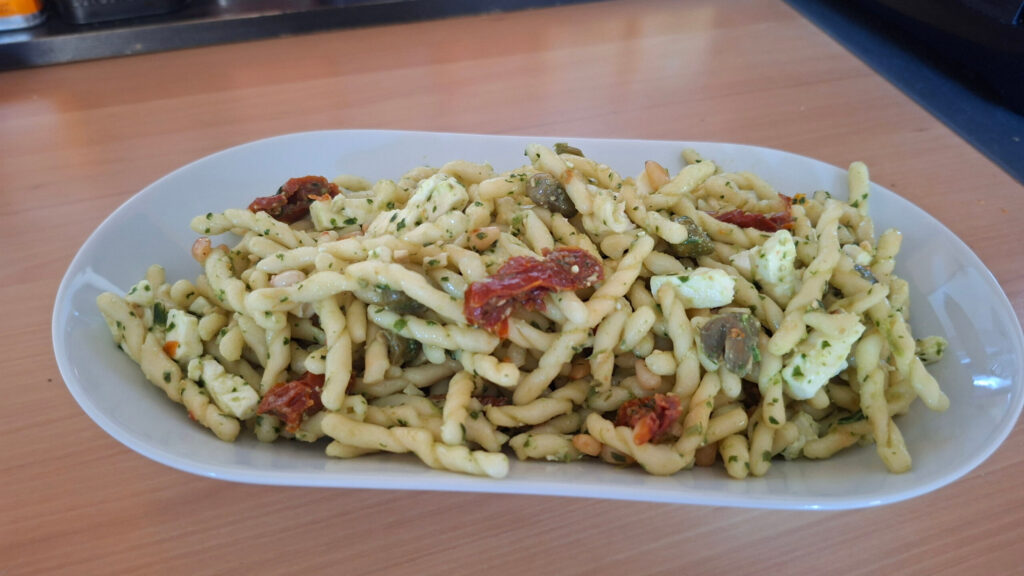 Pastasalade met feta, gedroogde tomaatjes, basilicumpesto, kappertjes en pijnboompitten