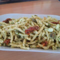 Pastasalade met feta, gedroogde tomaatjes, basilicumpesto, kappertjes en pijnboompitten