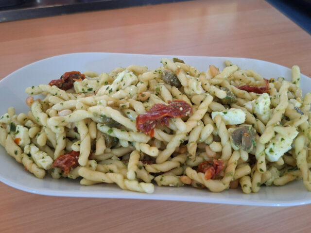 Pastasalade met feta, gedroogde tomaatjes, basilicumpesto, kappertjes en pijnboompitten