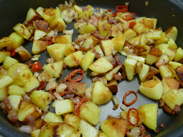 Pittige aardappeltjes met rode peper , spekjes , knoflook en sjalot.