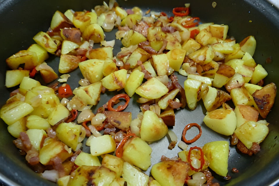 Pittige aardappeltjes met rode peper , spekjes , knoflook en sjalot.