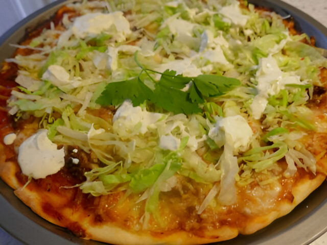 Pittige Gehaktpizza met ijsbergsla en lichte frisse knoflooksaus.