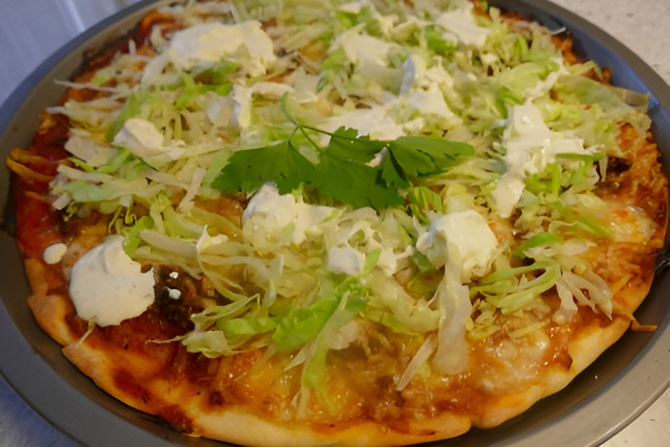Pittige Gehaktpizza met ijsbergsla en lichte frisse knoflooksaus.