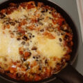 Shakshuka hoofdgerecht met zwarte bonen, wortel, courgette, champignons en paprika uit de oven