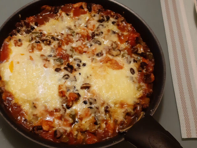 Shakshuka hoofdgerecht met zwarte bonen, wortel, courgette, champignons en paprika uit de oven