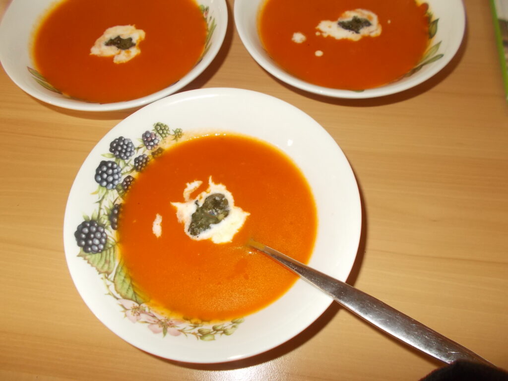 Pittig gekruide wortel-tomatensoep met sherry, basilicumpesto en room